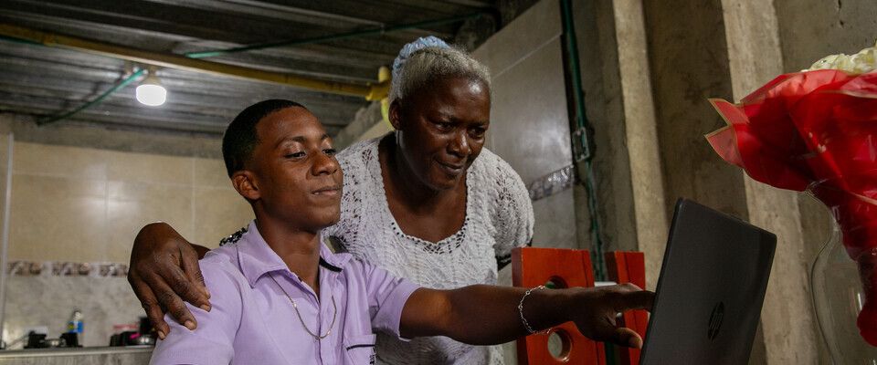 Foto de una señora adulto junto a un joven observando un computador